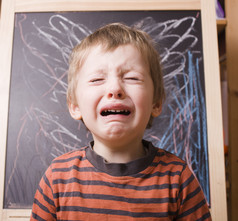 小可爱男孩尖叫和哭泣在学校附近黑板