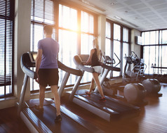 健康的男人和女人在健身房的跑步机上.