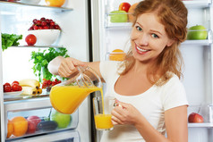 幸福的女人，对冰箱喝橙汁