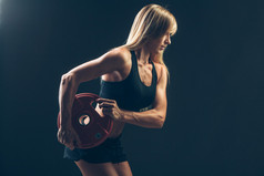 健身女人做重量训练，通过提升重物杠铃，体育生活方式