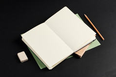 Open blank notepad with empty white pages laying above book with