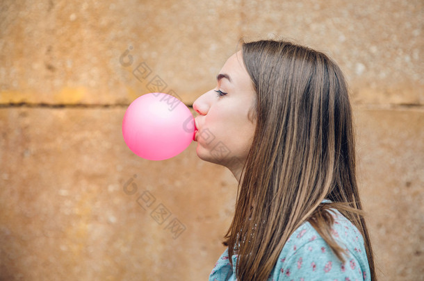 年轻少女吹粉红色泡泡糖