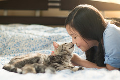 美丽的亚洲女孩亲吻美国短毛猫