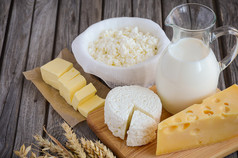 新鲜的乳制品。牛奶、 奶酪、 黄油和奶酪和小麦对仿古木制背景.