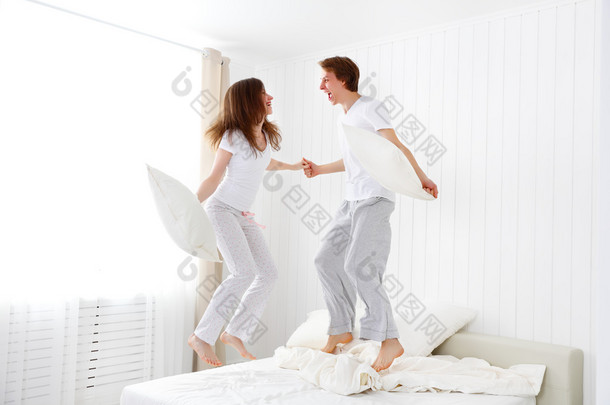 对幸福的夫妇跳跃和躺在床上乐趣