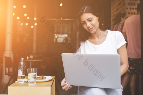 Young female student using laptop computer for learning while sitting in cafe