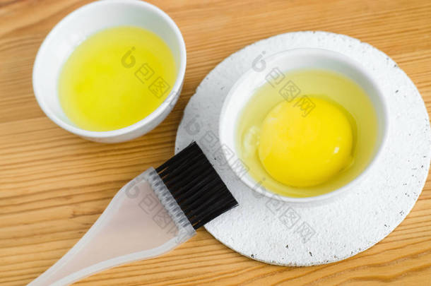 Raw egg and olive oil in a small ceramic bowls for preparing homemade face and hair masks. Ingredien