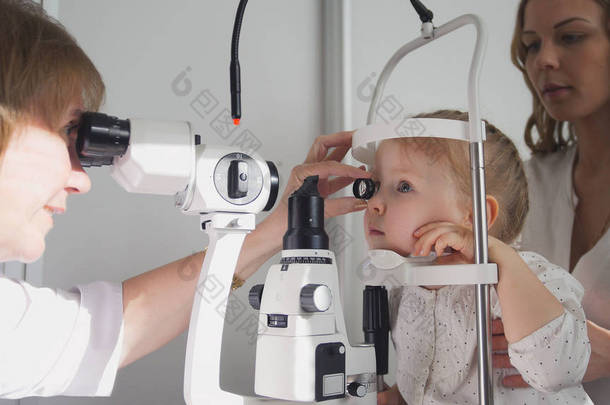 医生验光师检查小女孩视力-母亲和孩子在眼科医生的房间