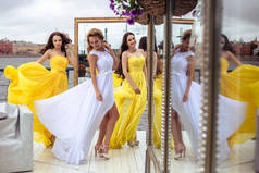 美丽的新娘和黄色相似的连衣裙上一个夏天在一起的两个伴娘露台海上餐厅