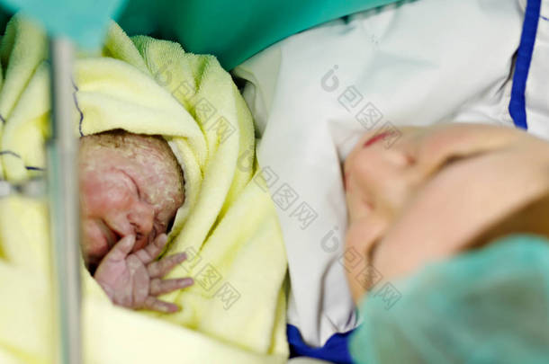 刚出生的婴儿在出生后包裹在毯子里。寻找第一次上新出生的女儿的母亲