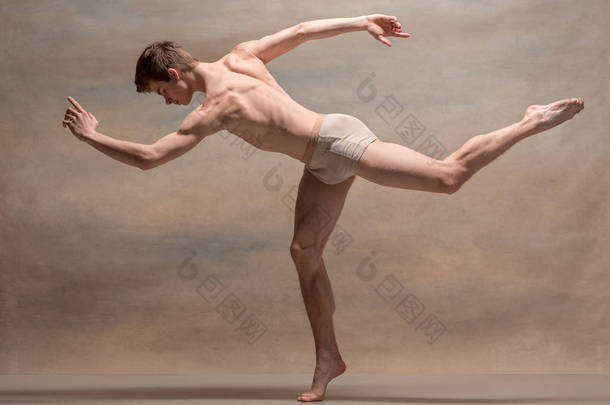 在灰色的背景构成的男芭蕾舞者