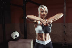 在健身房举重的肌肉发达的年轻健身女人