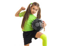 可爱的小女孩在玩足球的绿色制服
