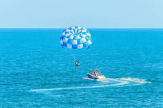 蓝色 parasail 翼拉扯了一艘船在海中，由水上滑翔伞