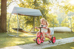可爱小金发女孩在夏天骑一辆自行车.
