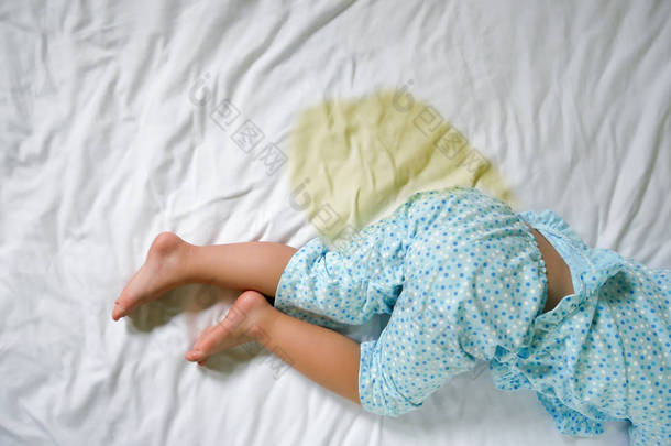 尿床： 孩子撒尿的床垫，小女孩的脚和尿在床上表中，儿童的发展概念，选择重点放在床上的湿