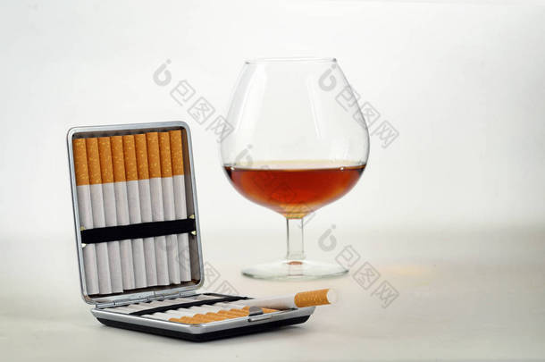 烟草和酒精、 烟盒带过滤嘴香烟和一杯白兰地酒或白兰地与副本空间浅灰色的背景上