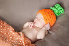 刚出生的婴儿，戴着针织的胡萝卜或南瓜帽子