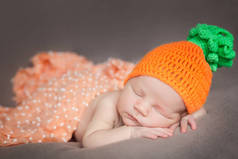 刚出生的婴儿，戴着针织的胡萝卜或南瓜帽子