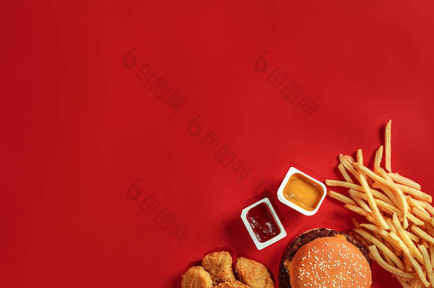 汉堡和薯条。汉堡包和炸薯条红纸框中。红色背景上的快餐食品.