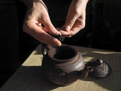 女人睡在粘土茶壶茶。紫砂壶。茶礼。在女性手中茶.