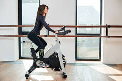 肌肉发达的年轻女子在健身房练自行车，做高强度的有氧运动.