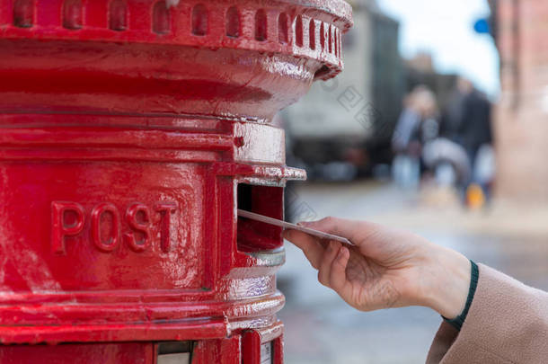 把一封信扔进红色的英国邮政信箱