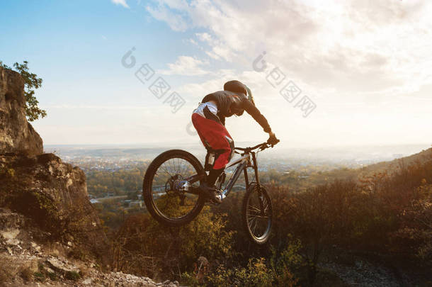 一个年轻的骑手在他的山地自行车的车轮在秋季森林下山的<strong>跳板</strong>上跳跃的伎俩