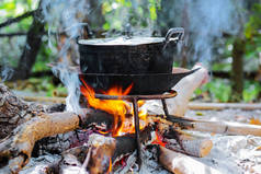 用旧的黑蒸煮锅和烟雾在壁炉里燃烧木柴