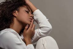 年轻温柔的非洲裔美国妇女在白色的衬衫触摸嘴唇孤立的灰色背景