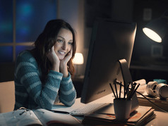 愉快的妇女在晚上使用她的计算机