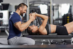 私人教练帮助女性在健身房锻炼三头肌