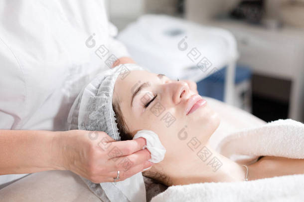 用消毒过的餐巾擦拭脸.年轻漂亮的女人在<strong>美容院</strong>接受治疗。使用<strong>洗脸</strong>泡沫.