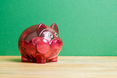 红色的小猪银行和绿色背景的硬币罐。储蓄与投资理念.