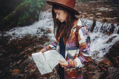 癖和旅游理念。时尚的旅游女孩在帽子里看地图, 探索树林。在森林里的河里背包旅行的时髦女人。文本空间