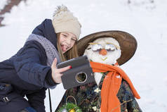 快乐的小女孩正在用雪人给自拍拍照