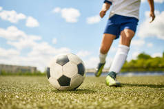 低剖面肖像的不识别青少年男孩踢球在足球场练习, 专注于足球躺在草地上