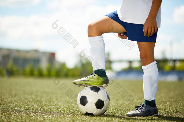 站在足球场上的不被辨认的年轻运动员的侧面看法画像在<strong>橄榄球</strong>场与腿在球