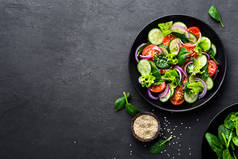新鲜西红柿、黄瓜、洋葱、菠菜、生菜和芝麻的健康蔬菜沙拉。饮食菜单。顶部视图.