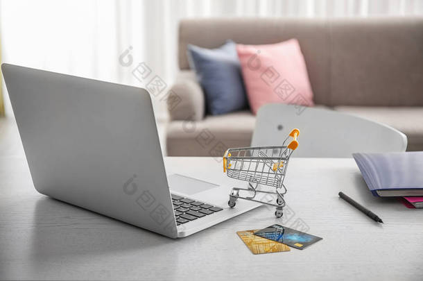 笔记本电脑, 小购物车和信用卡在桌子上。网络购物理念