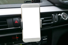 在导航或 Gps。 驾驶一辆带有智能手机持有人在车上使用的智能手机。孤立的白色屏幕的手机。空白的空白屏幕。复制空间。文本的空白空间。现代汽车内部的细节.