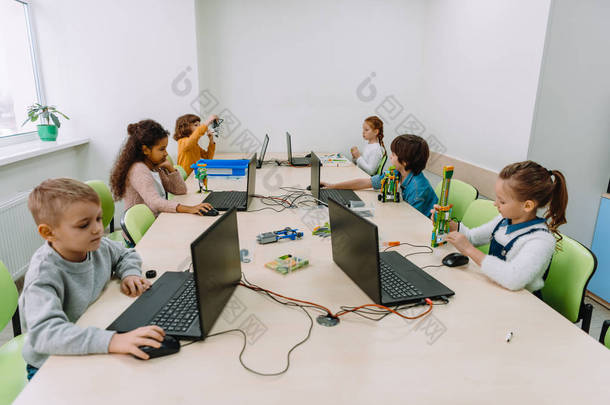 一群专注于计算机的儿童在机械类上工作