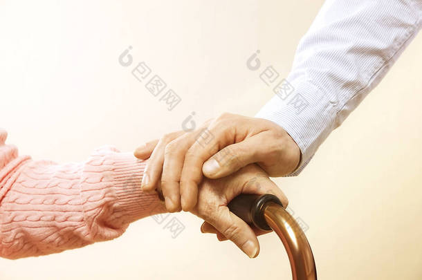 老年护理机构的成熟女性得到医院人事护士的帮助。老妇人皱起了皱纹的手。盛大母亲日常生活.