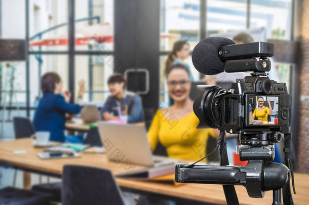 专业的数字无镜摄像头与麦克风录制视频博客的女商人工作与集团的商业人士。照相机为摄影师或录影和实况流动概念
