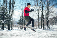 全长的青年男子跳在冬季雪公园