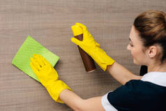 用抹布和气溶胶家具清洁剂均匀擦拭木墙的年轻女仆特写镜头