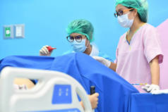 亚洲男性产科医生和护士被送到病人躺在医院产房的床上。