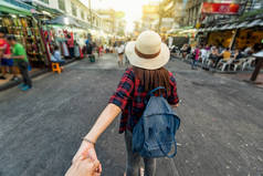 年轻的亚洲旅行妇女领导通过举行她的男朋友手在考山路步行街晚上在泰国曼谷, traveleling 一起和游客跟着我的概念