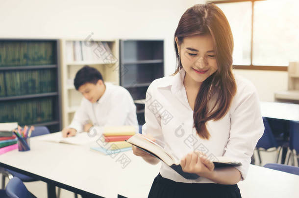 年轻的亚洲学生在图书馆读一本书。<strong>教育理念</strong>.