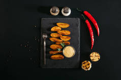 在石板板和香料与大蒜和辣椒辣椒在黑色的美味烤土豆的顶级视图